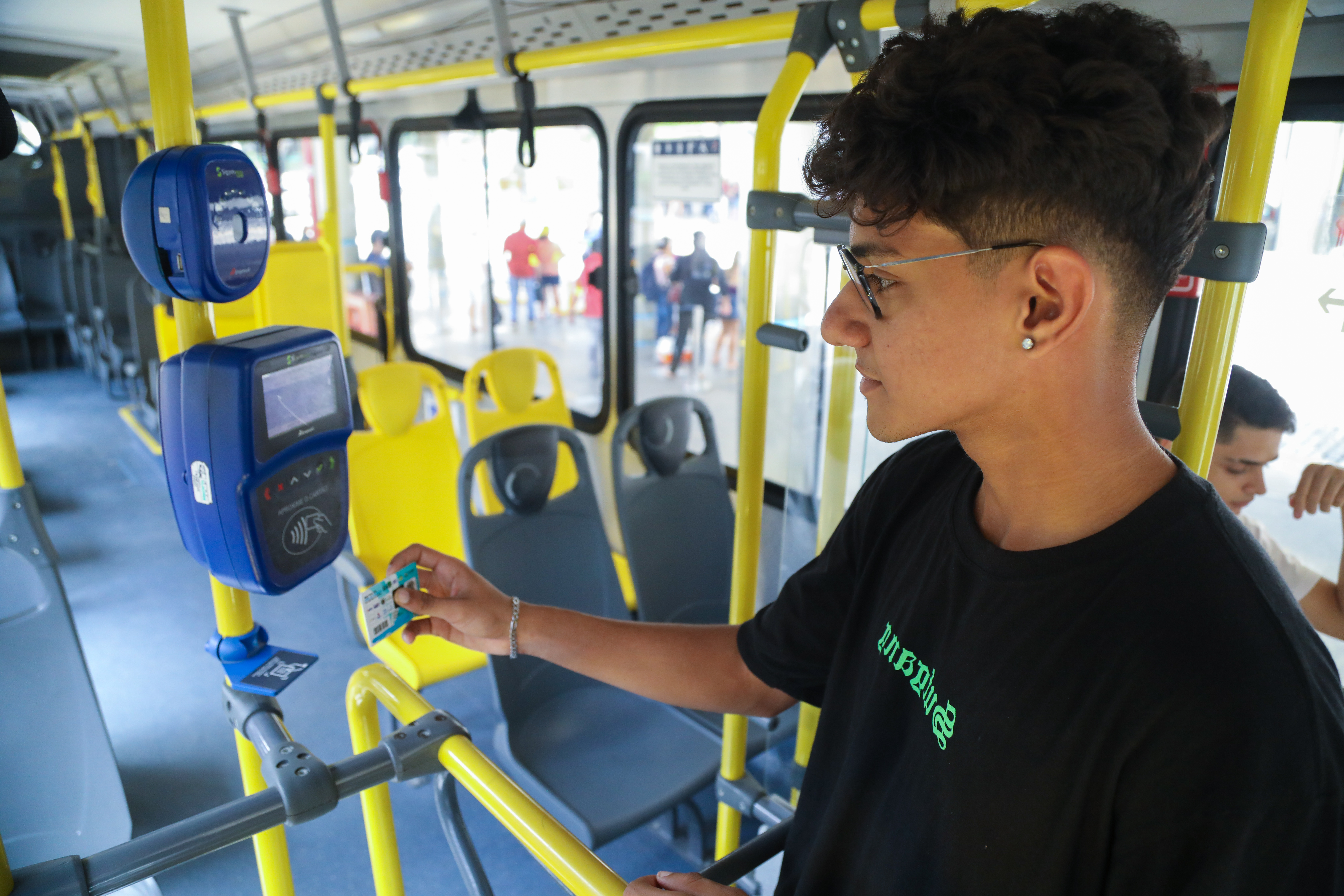 estudante passando a carteira no leitor do ônibus